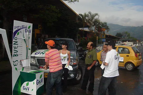 Promotores de GNV conversando con taxistas junto a un juego de fuerza
