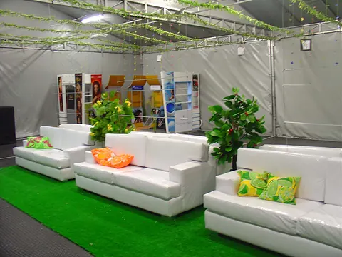 Amoblamiento de una carpa para evento con sofás blancos, cojines de colores y grama sintética