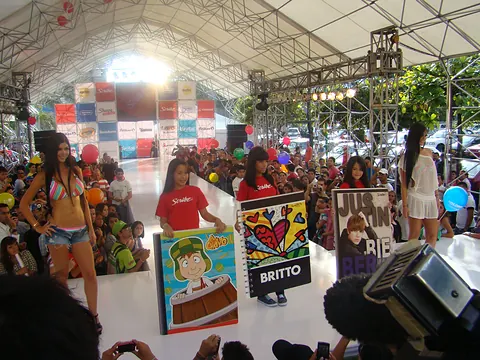 Desfile de temporada escolar de Éxito con modelos y cuadernos gigantes frente a un público numeroso