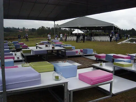 Lounge al aire libre para el lanzamiento de la Biofábrica de Semillas, con mesas bajas y cojines de colores bajo una carpa