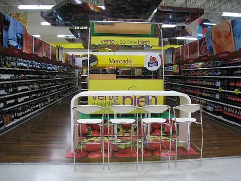 Mueble de degustación blanco y amarillo entre estanterías de un supermercado