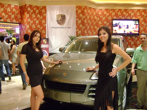 Dos modelos con vestido negro junto a una camioneta Porsche en exhibición en Colombiamoda