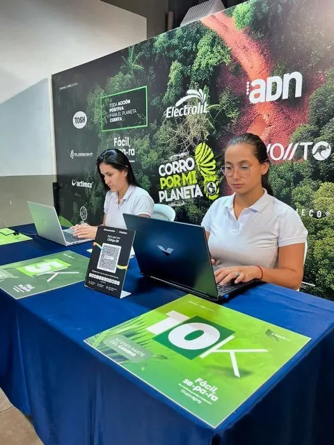 Personal de registro con computadores en la mesa de inscripción de una carrera 10K