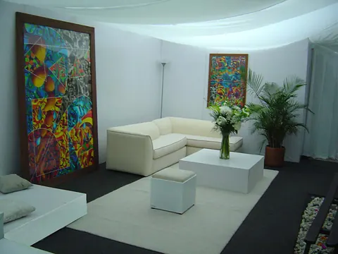 Sala VIP para un evento, con sofá blanco, mesa de centro y obras de arte