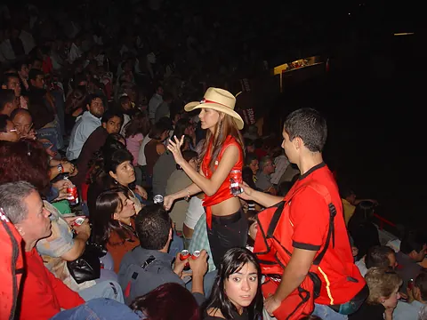 Promotoras con sombrero entregando muestras de producto al público en un evento nocturno