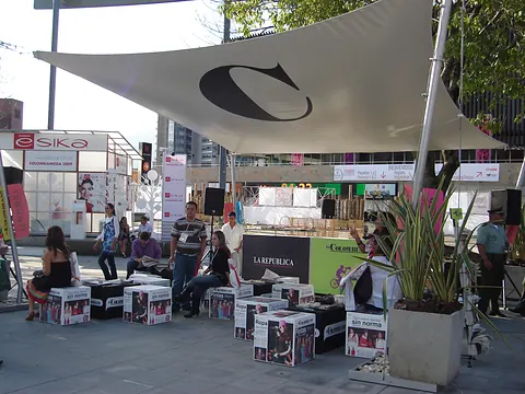 Stand de El Colombiano para una feria al aire libre, con cubierta tensada blanca y asientos