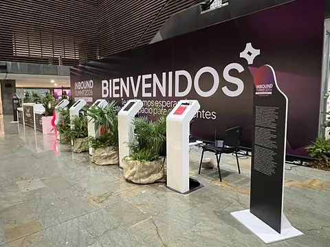 Zona de registro del Inbound Summit 2026 con muro de bienvenida, tótems blancos de acreditación y plantas